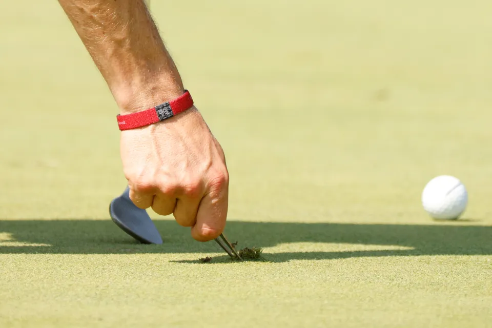 A golfer repairs a pitchmark on the green