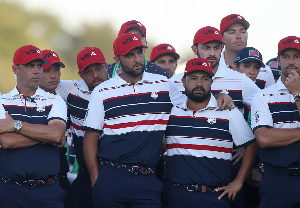 Scottie Scheffler of Team United States and teammates stand together on the 18th green after being defeated by Team Europe during the Sunday singles matches of the 2025 Ryder Cup